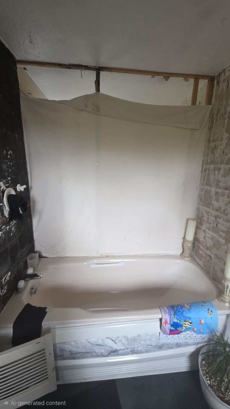 Bathtub with white shower curtain in small tiled bathroom, bedding and supplies stored below rim
