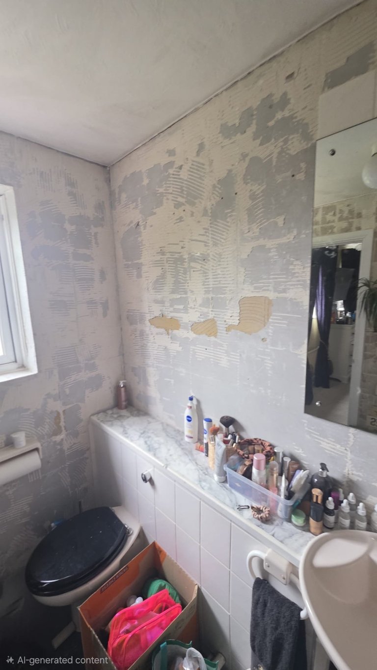 Bathroom with partially demolished walls showing drywall underneath, black toilet, white vanity with cosmetics, and a mirror