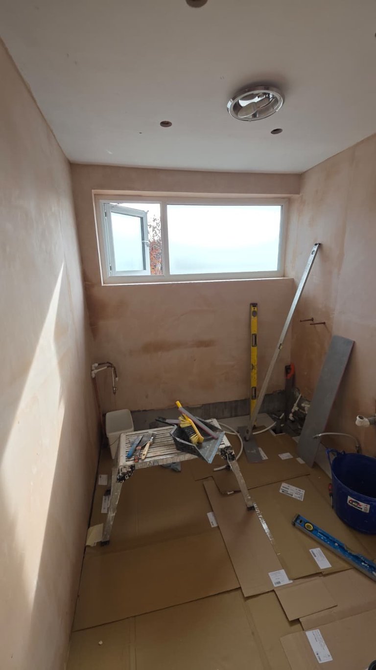 Bathroom under renovation with drywall, work tools, ladder, and window during construction