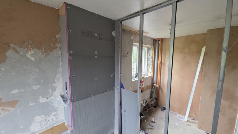 Unfinished drywall construction with glass partition and exposed framing in renovation project